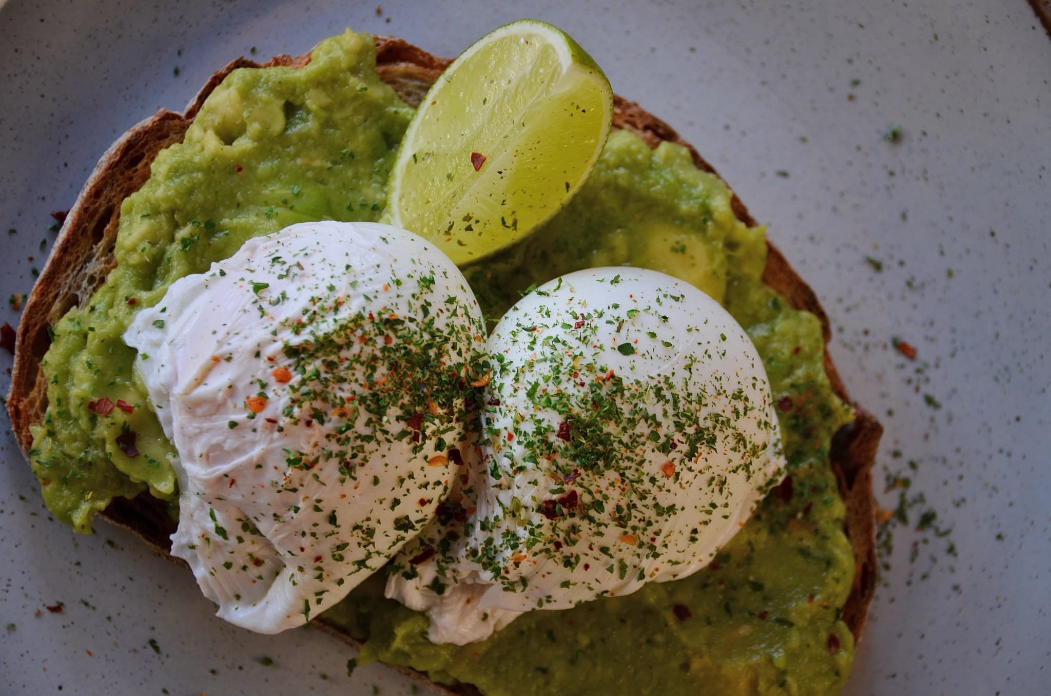 Smashed avocado and poached eggs on toasted sourdough with chilli herbs and lime