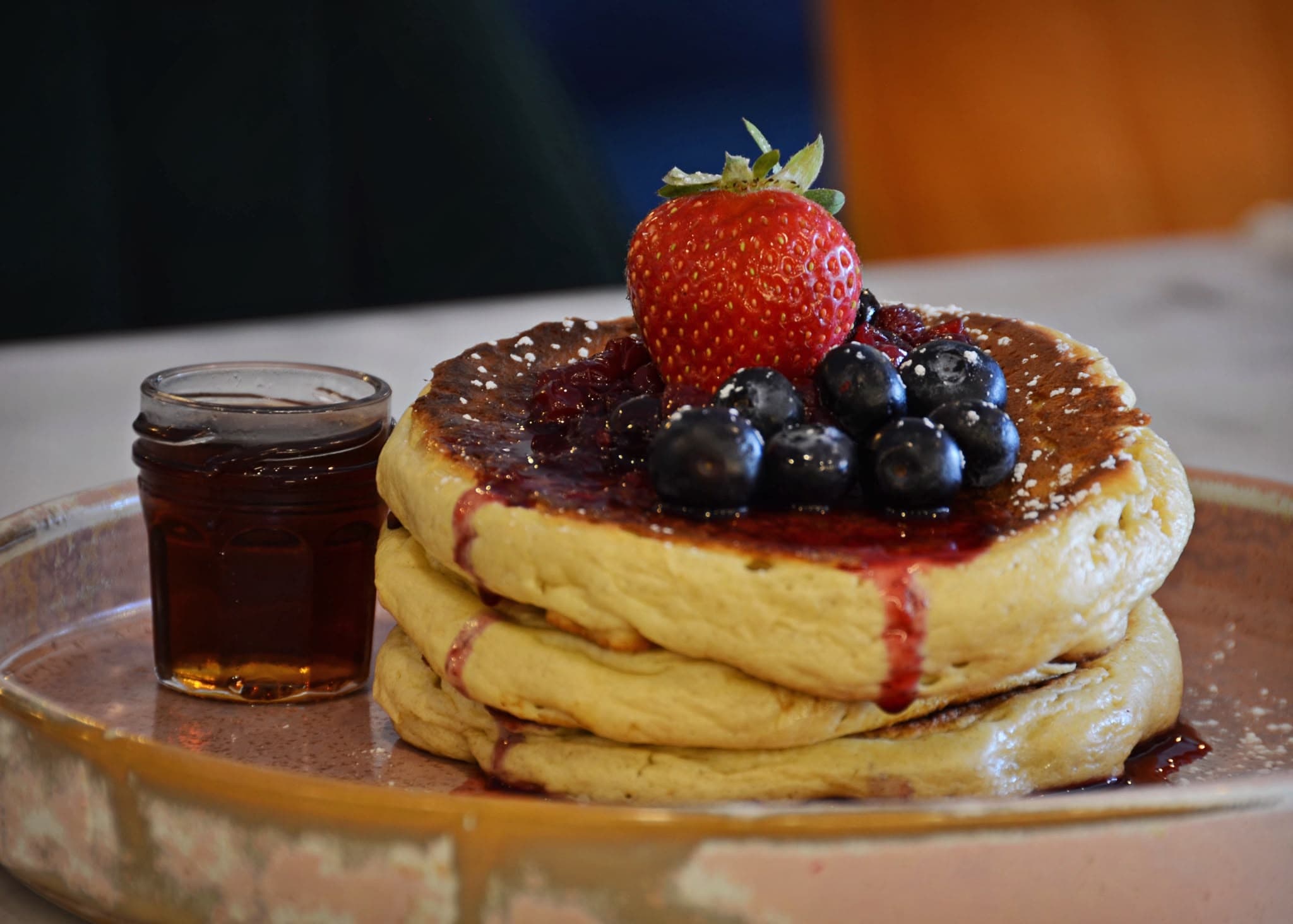 Stack of buttermilk pancakes with fresh berries and maple syrup
